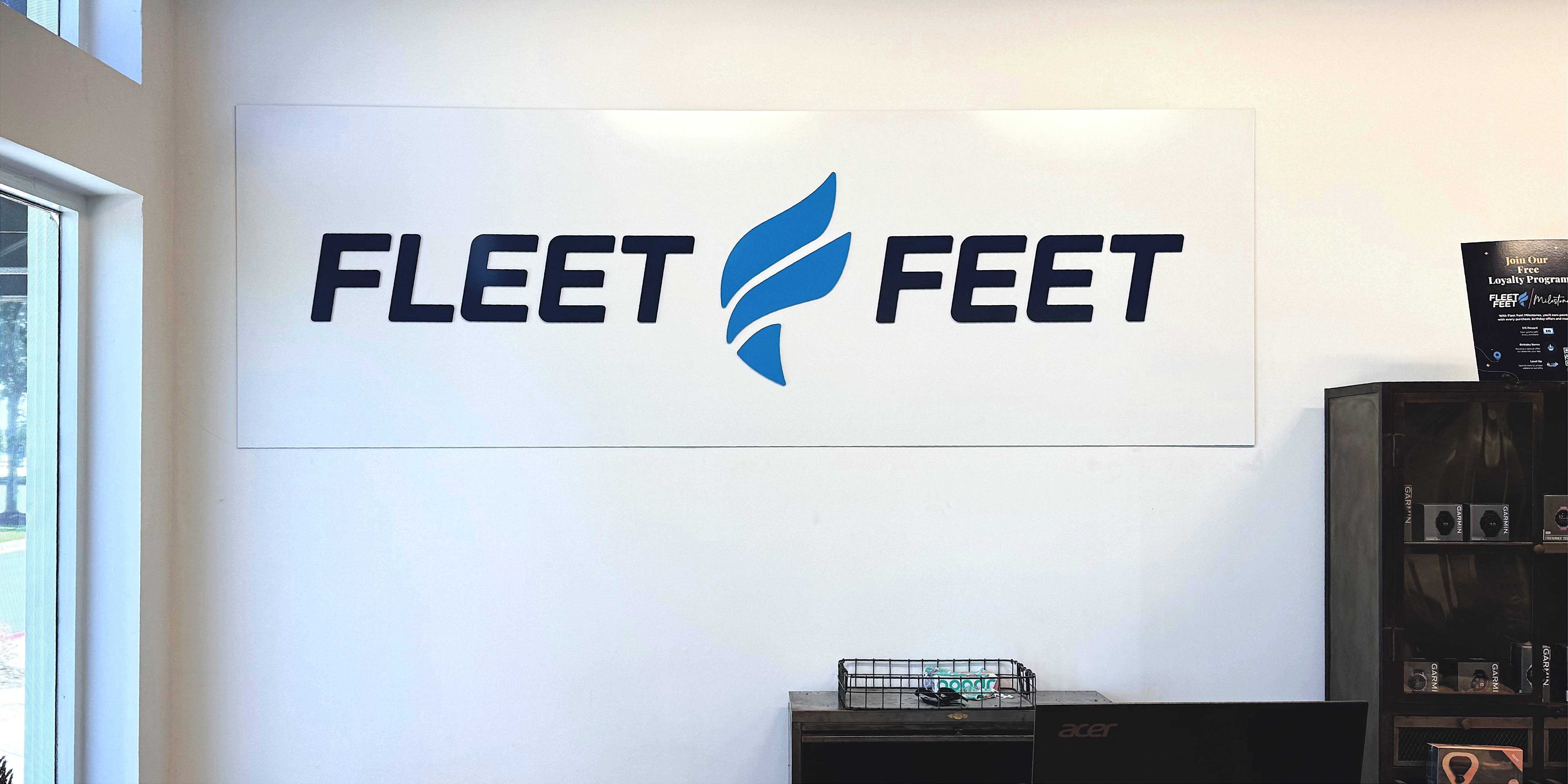 panel sign that says Fleet Feet mounted to wall