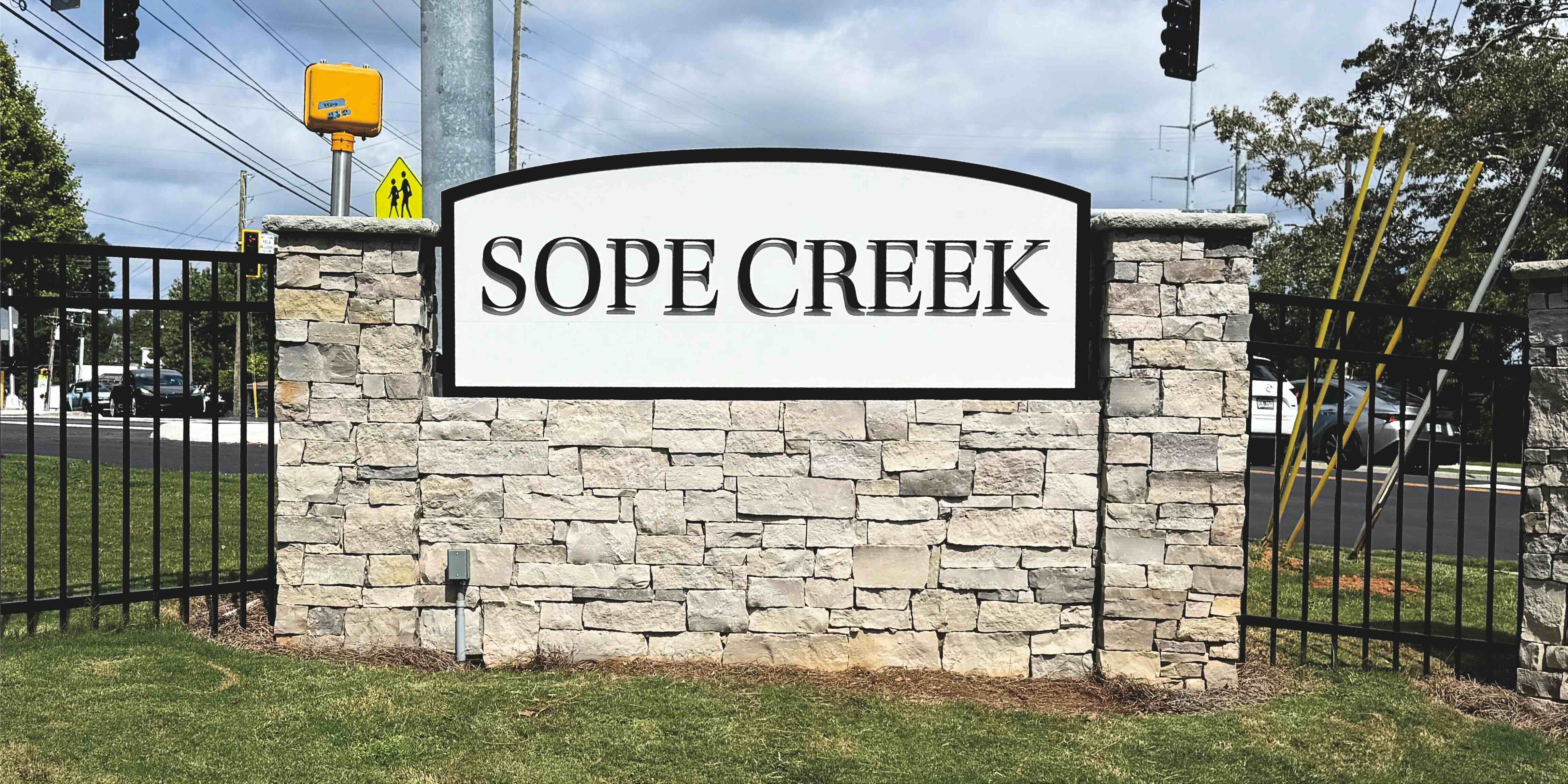 sopecreek sign on brick facade in grass next to road